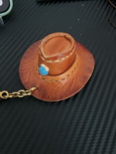 a brown leather hat with a blue bead on it's chain sitting on a table