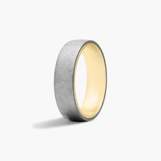 a yellow and grey wedding ring on a white background