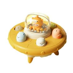 a yellow toy with animals in it on top of a small table and some eggs