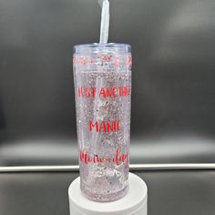 a tumbler cup sitting on top of a white stand with red writing and a straw sticking out of it