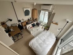 an aerial view of a living room with a bed, couch and desks in it