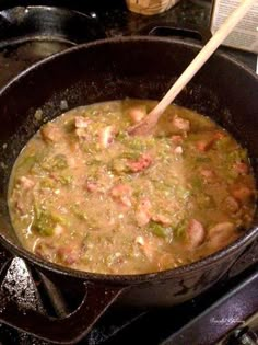 a pan filled with food sitting on top of a stove next to a wooden spoon