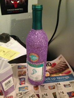 a purple bottle sitting on top of a table next to a pile of coupons