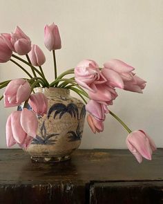 a vase with pink flowers on top of a wooden table