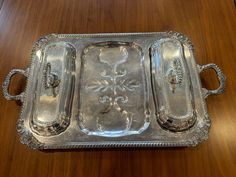 an ornate silver tray with handles on a wooden table