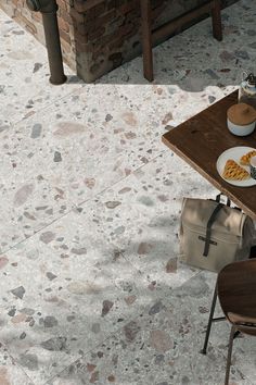 a table with plates of food on it next to a chair and brick wall in the background