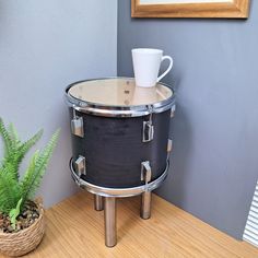 a coffee cup is sitting on top of a black drum case next to a potted plant