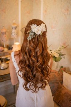 the back of a woman's head with long hair and flowers in her hair