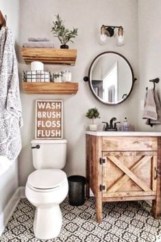 a white toilet sitting next to a wooden cabinet in a bathroom under a round mirror