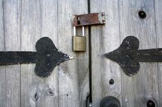 an old wooden door with two padlocks on it