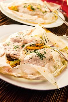 two plates with food on them sitting on a table next to wine glasses and utensils