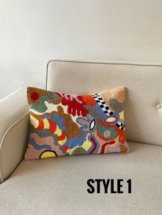 a white couch with a multicolored pillow on it and the words style 1 written below