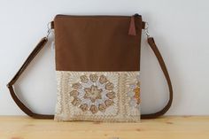 Bolso de lona en color marrón, combinado con tela estampada con motivos de ganchillo. Esta hecho con tela de alta calidad. El asa está hecha con la misma lona, acolchada para darle mayor resistencia, con un regulador para que puedas ajustarla  ala medidas que quieras, tanto cruzado como para llevar en el hombro. No tiene bolsillos, el compartimento principal se cierra con una cremallera que acaba en un tirador de cuero marrón. Forrado con tela acolchada. Muy practico para llevar a diario y muy c Brown Mobile Phone Bag For Fall, Casual Brown Clutch Shoulder Bag, Brown Canvas Bag For Fall, Brown Canvas Bag For Daily Use In Fall, Brown Canvas Shoulder Bag With Adjustable Strap, Brown Crochet Clutch Bag With Removable Pouch, Brown Crochet Bag With Removable Pouch For Travel, Brown Canvas Crossbody Bag With Removable Pouch, Bohemian Brown Bags For Fall