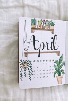 an open notebook with the word april written on it and potted plants next to it