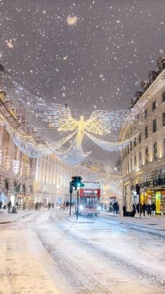 a snowy city street with people walking on the sidewalks and buildings covered in lights,