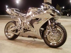 a silver motorcycle parked on top of a parking lot next to a street light at night