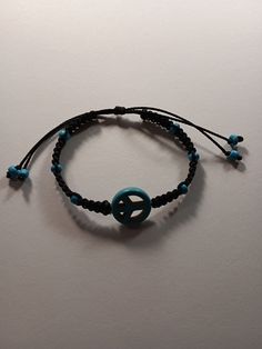 a bracelet with a peace sign on it and blue beaded beads hanging from the end