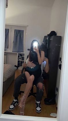 a woman taking a selfie in front of a mirror while sitting on a chair