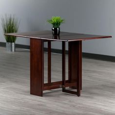 a small potted plant sits on top of a wooden table in an empty room