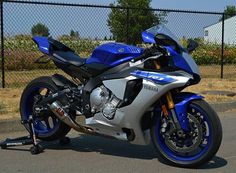 a blue and silver motorcycle parked in front of a fence