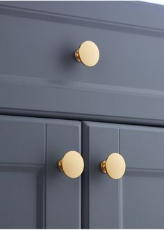 a gray dresser with gold knobs and two doors on the front, one door is open