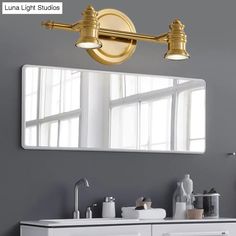 a bathroom vanity with two lights and a mirror above it, in front of a window