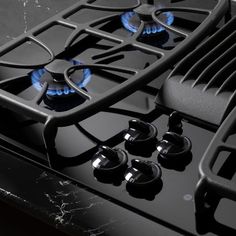 a black gas stove with blue flames on it