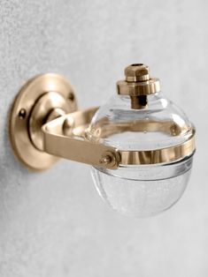 a close up of a wall mounted glass jar on a metal hook with a white background