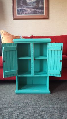 a blue cabinet sitting on top of a carpeted floor next to a red couch