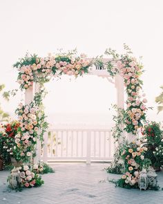 an outdoor wedding setup with flowers and greenery on the side of the ceremony arch