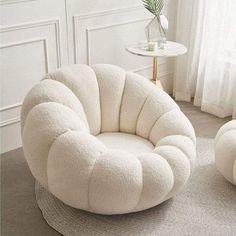 a white chair and ottoman on a rug in a living room with a potted plant