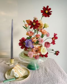 there is a cake with flowers on it and a candle next to the cake plate