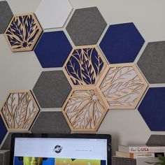 a laptop computer sitting on top of a desk next to a wall covered in hexagonal