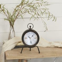 an alarm clock sitting on top of a wooden table next to a potted plant