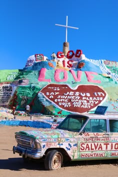 an old station wagon parked in front of a colorfully painted building with a cross on top