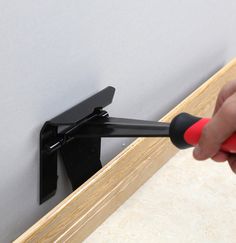 a person is using a screwdriver to fix a wall mounted mirror with black brackets