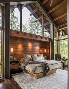 a large bed sitting in the middle of a bedroom next to a wooden wall and windows