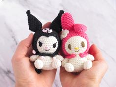 two small crocheted stuffed animals are held in their hands, one is black and the other is white