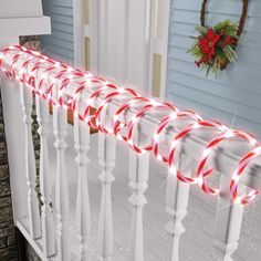 a set of red and white christmas lights sitting on top of a banister in front of a house