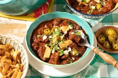 two bowls filled with chili, cheese and tortilla chips on top of a table