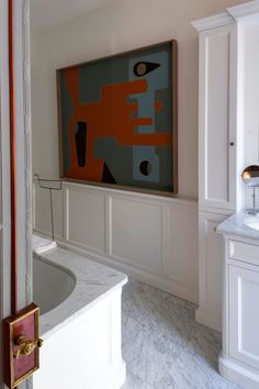 a large painting hangs on the wall above a bathtub in a bathroom with marble floors and walls