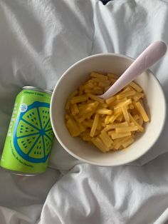 a bowl of macaroni and cheese next to a can of soda