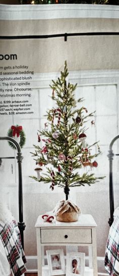 a small christmas tree sitting on top of a white table next to a bed in a room