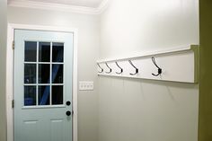 the door is open and there are three hooks hanging on the wall above the door