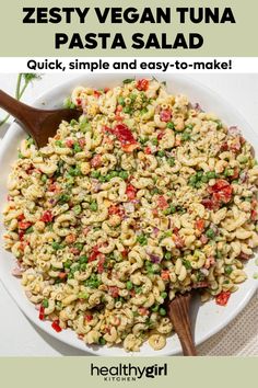 a bowl filled with pasta and vegetables on top of a white plate next to a wooden spoon