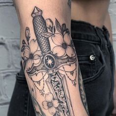 a woman's arm with a cross and flowers on it