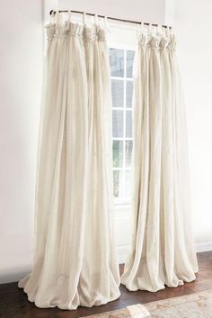 two white curtains hanging on the side of a window