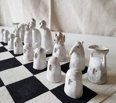 several white ceramic figurines sitting on top of a black and white checkered table cloth