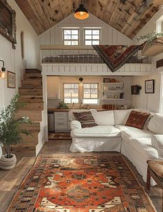 a living room filled with furniture and a rug on top of a wooden floor next to stairs