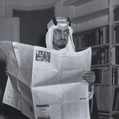 a man reading a newspaper while wearing a headdress